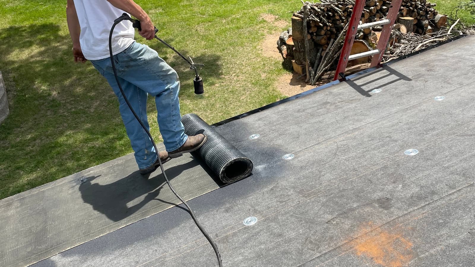 Roofer using a torch to install membrane on a flat roof