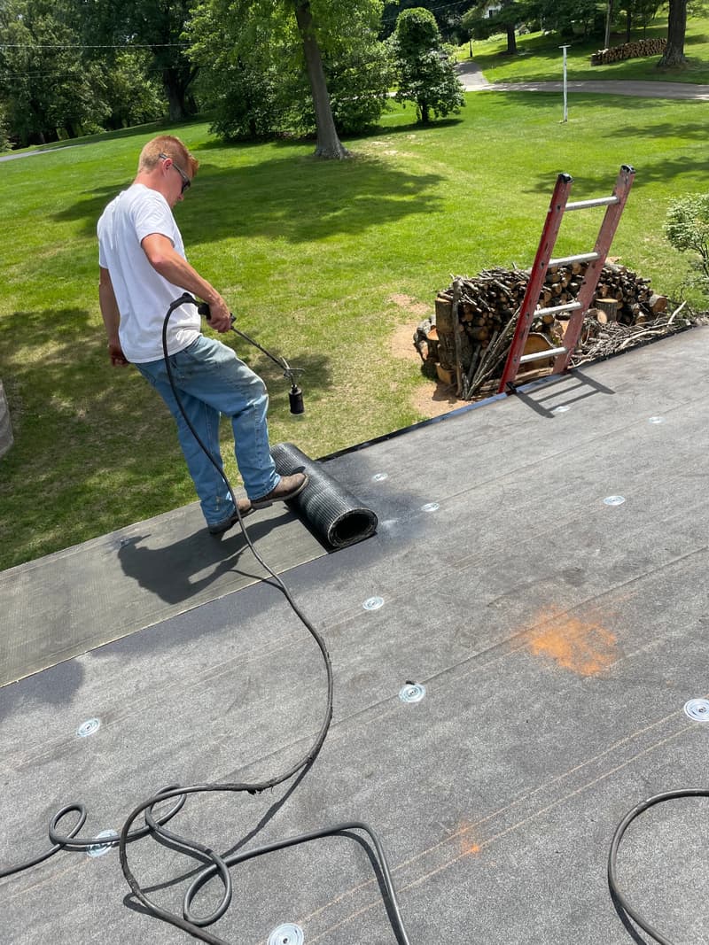 Roofer using a torch to install membrane on flat roof