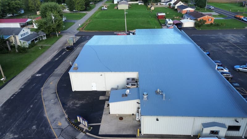 Aerial view of large commercial building with blue metal roof